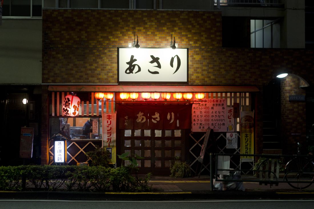 Noren curtains hanging at the entrance of Akari izakaya at night
