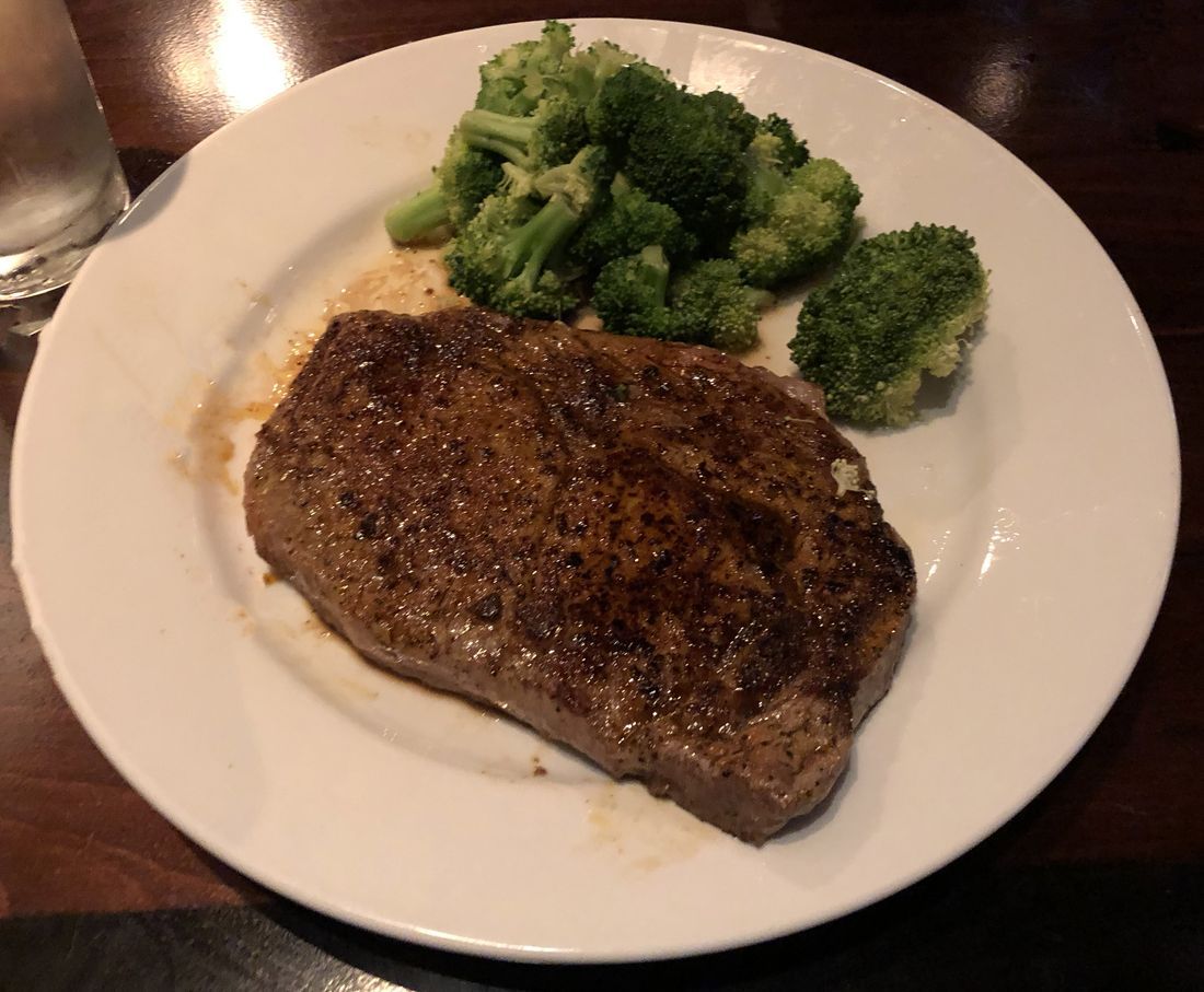 A charcoal-grilled ribeye steak resting on a wooden board